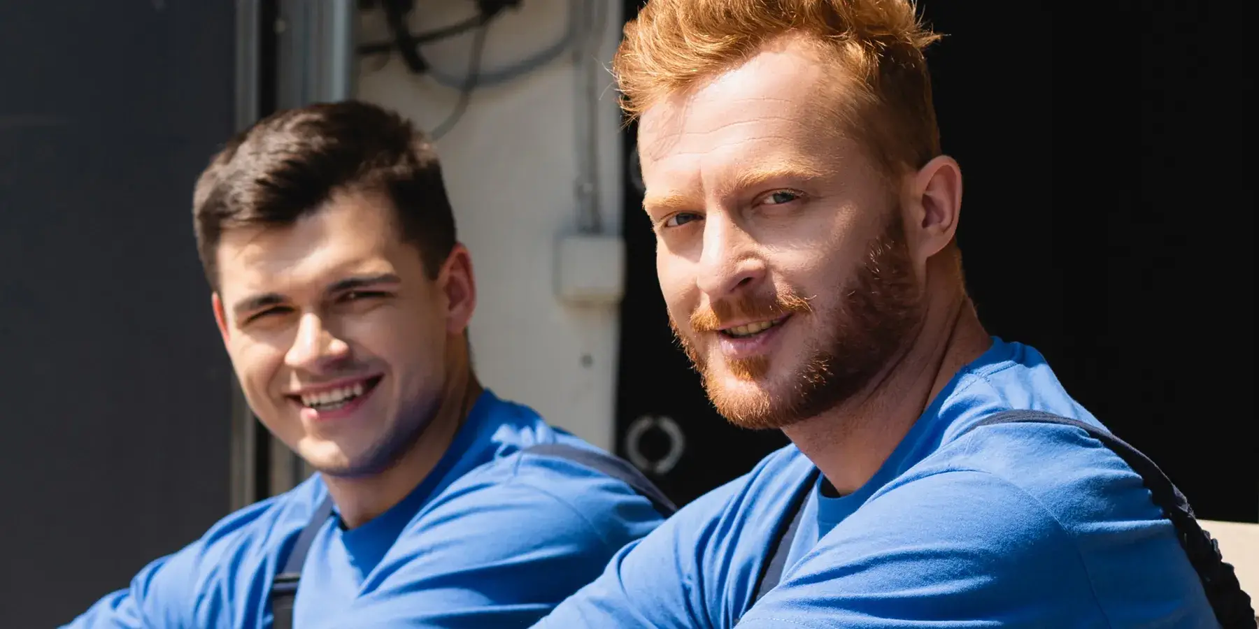 Two friendly Budget Movers crew members smiling in front of a moving truck