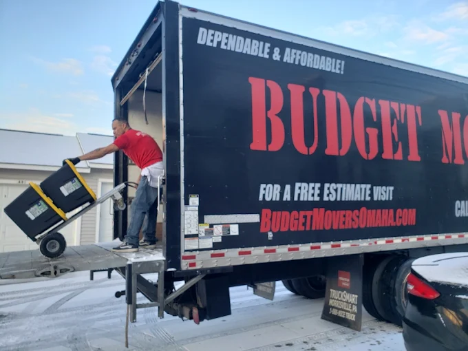 Budget Movers crew member unloading equipment from a black moving truck