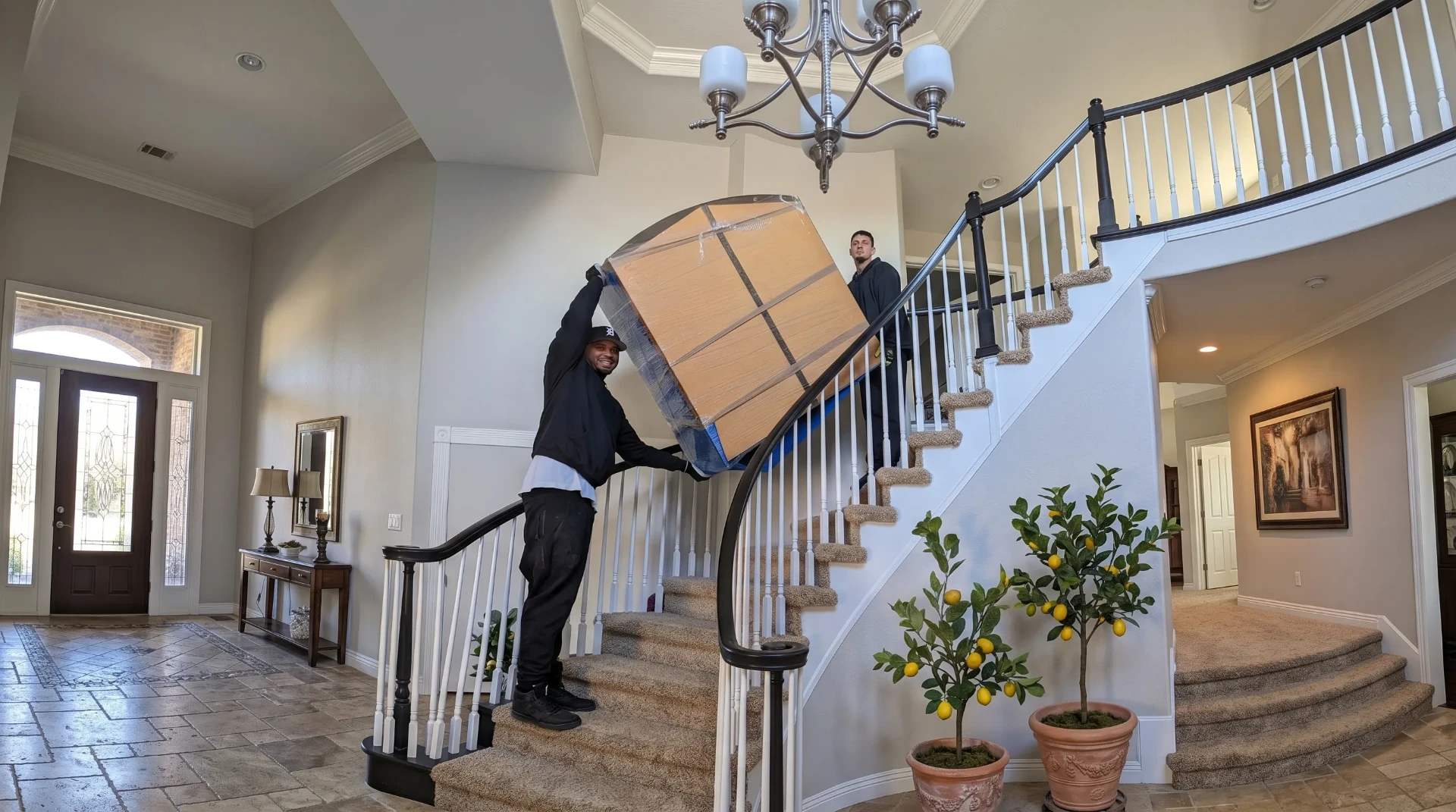 Budget Movers professionals carefully carrying a large box up a staircase