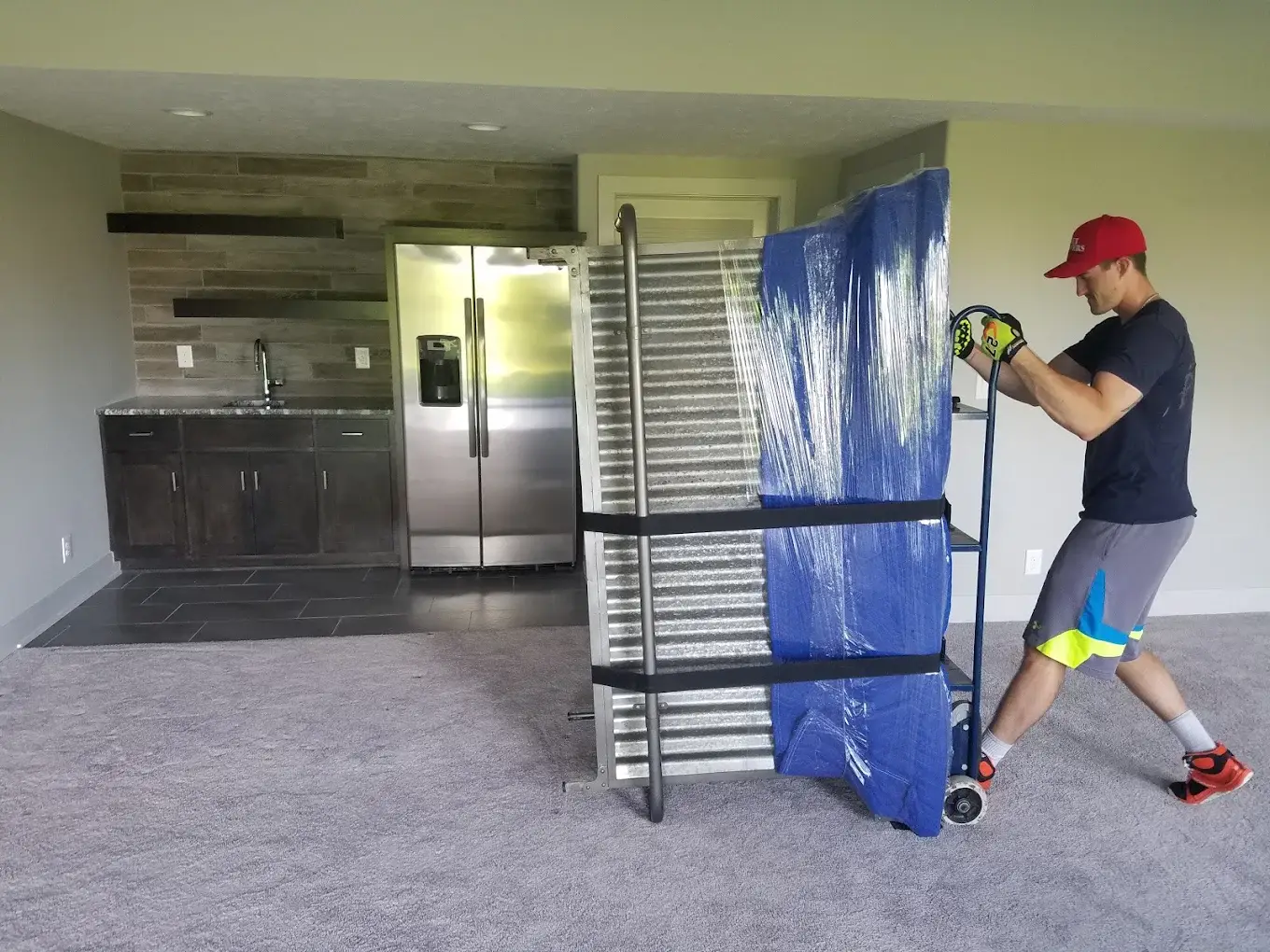 Budget Movers crew member moving a wrapped panel through a finished basement